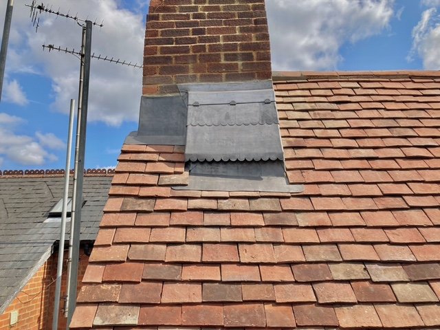 Close-up of leadwork around a chimney on a tiled roof