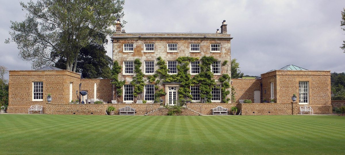 Exterior shot of a period home with brick facade and manicured lawn.