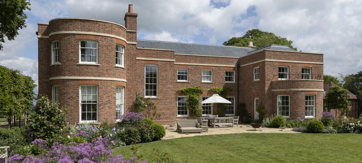 Exterior shot of a brick period home with a circular tower and garden.