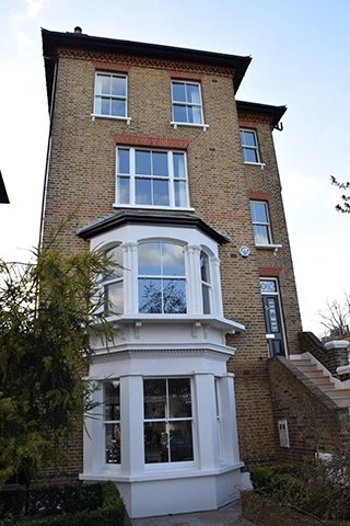 Full view of a house with multiple sash windows, including a bay window.