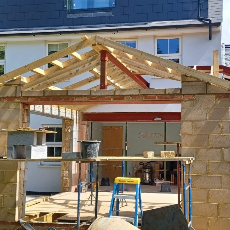 Construction of a building extension with exposed brick and wooden beams.