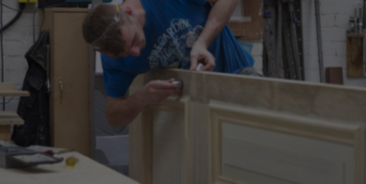 A craftsman working on a door, demonstrating the bespoke joinery aspect of the business.