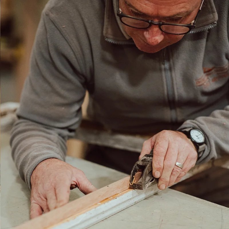 Carpenter using hand plane on timber
