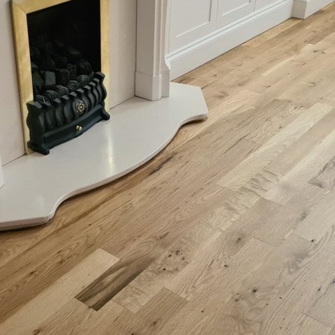 Wooden floor after sanding and polishing near a fireplace