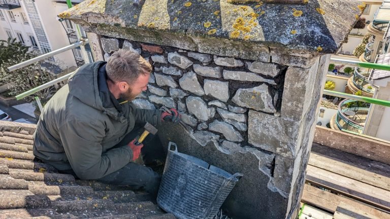 Mason working on a stone chimney restoration.