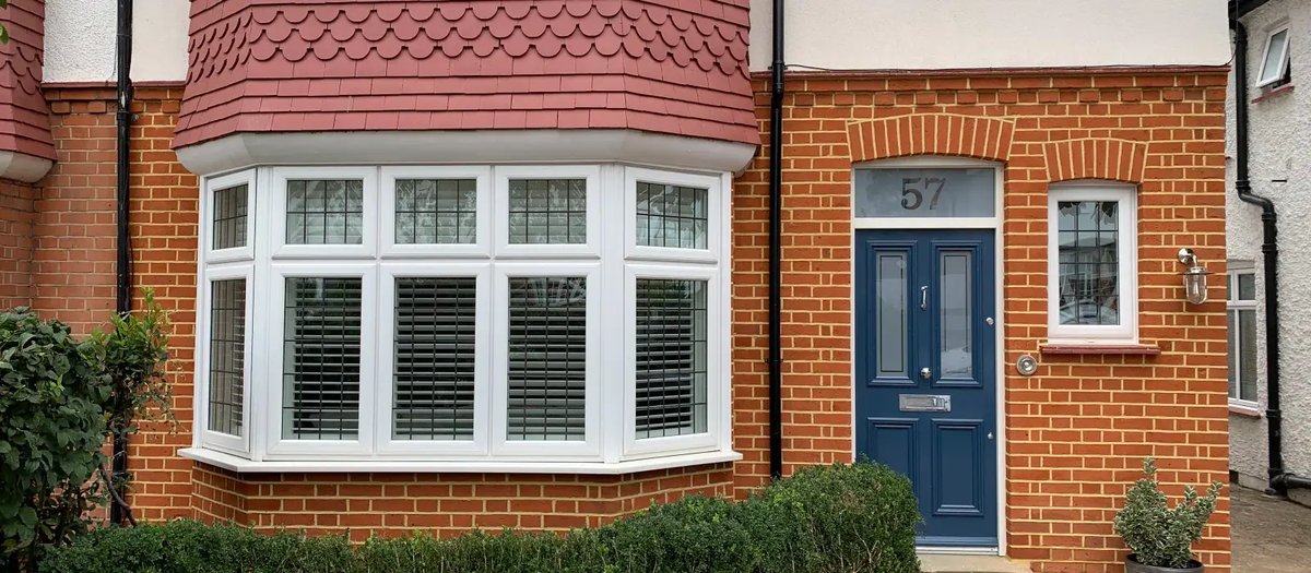 Restored brick facade of a period home with a new bay window and repainted door.