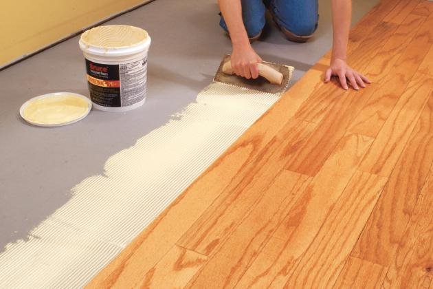 Applying adhesive for wood flooring installation.