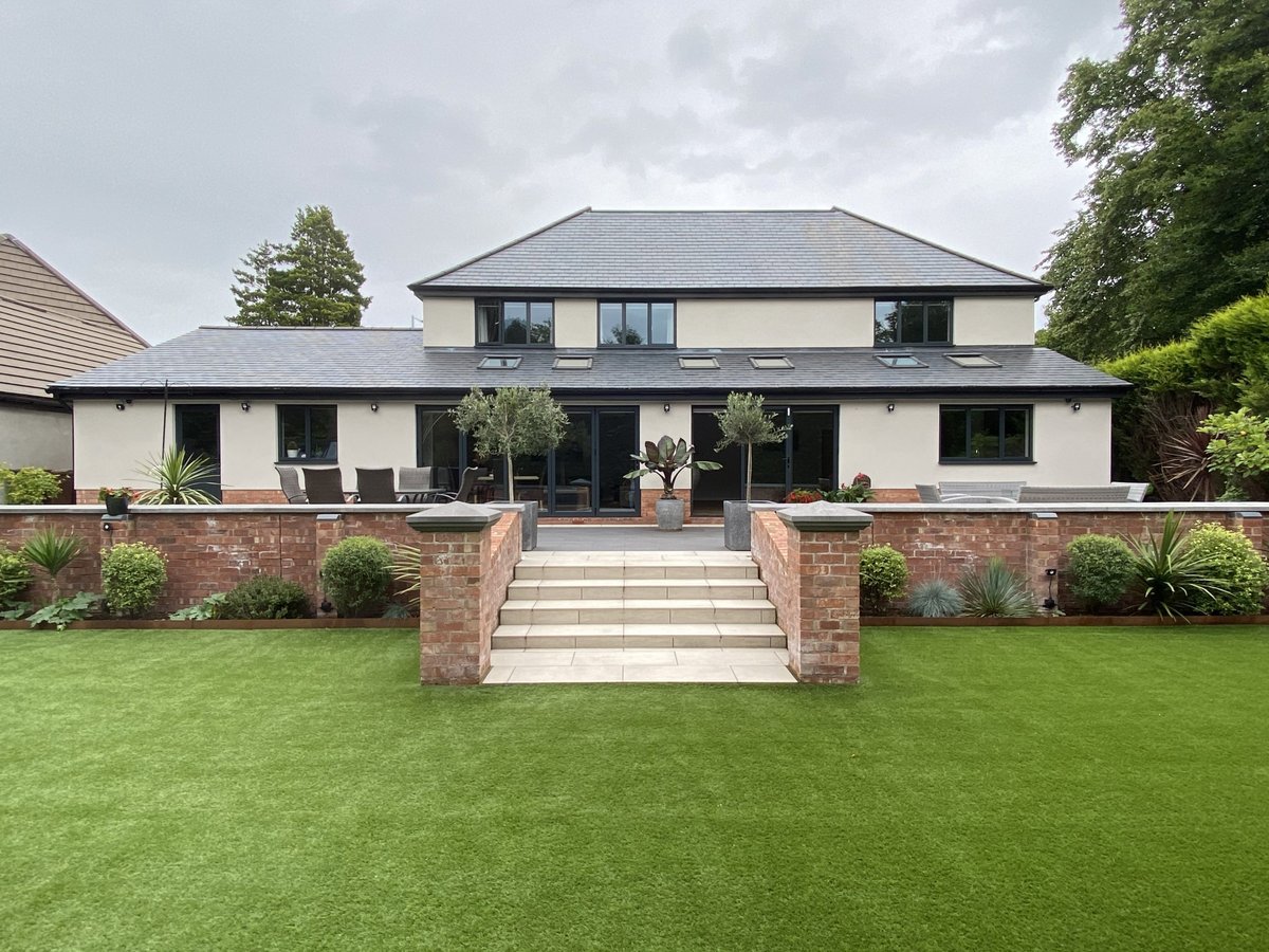 Rear view of a modern home with a large garden, showcasing potential custom build projects.