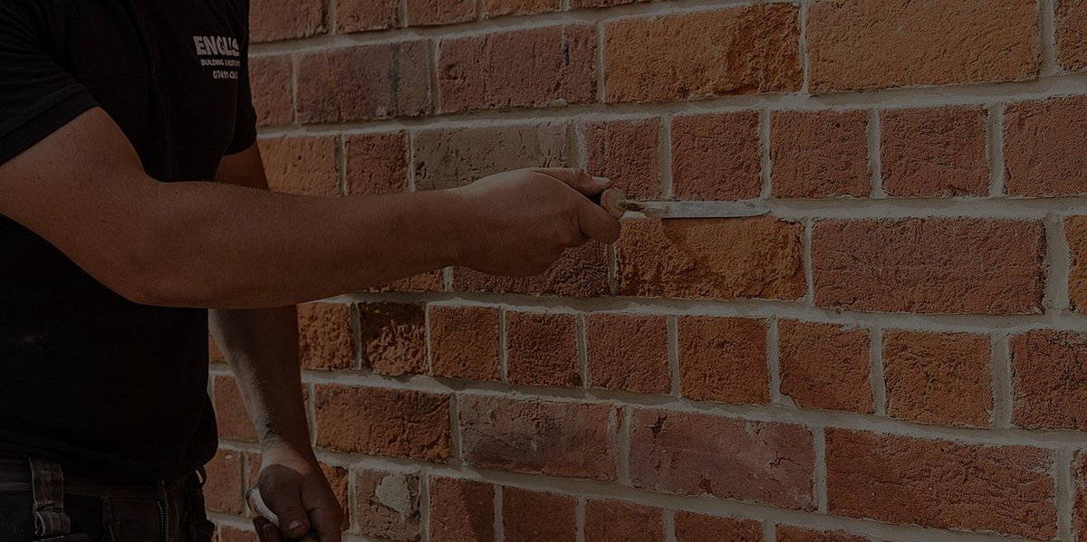 Close-up of bricklayer working on brick wall, highlighting their bricklaying skills.