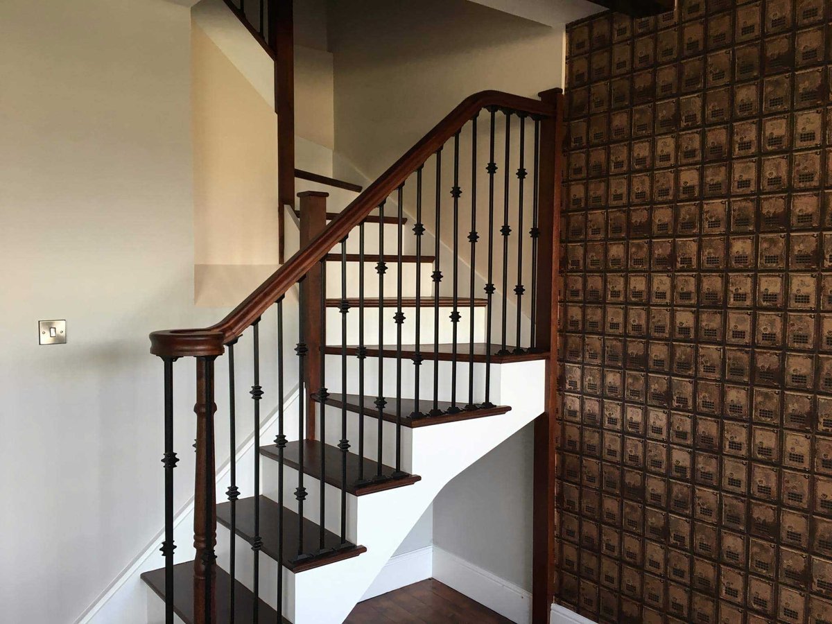 Finished staircase with dark wood and black metal railings.