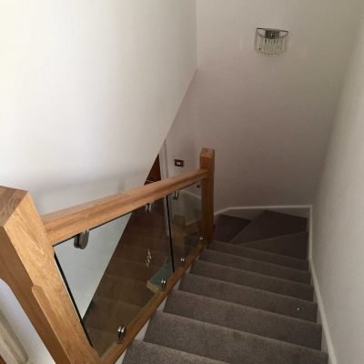 Finished staircase with glass and wood railing.