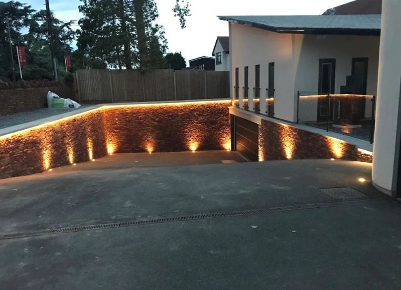 Stone retaining wall with lighting, showcasing masonry skills.