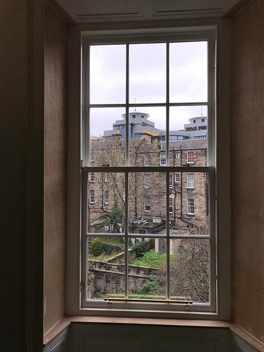 Interior view of a restored sash window with a view of Edinburgh buildings.