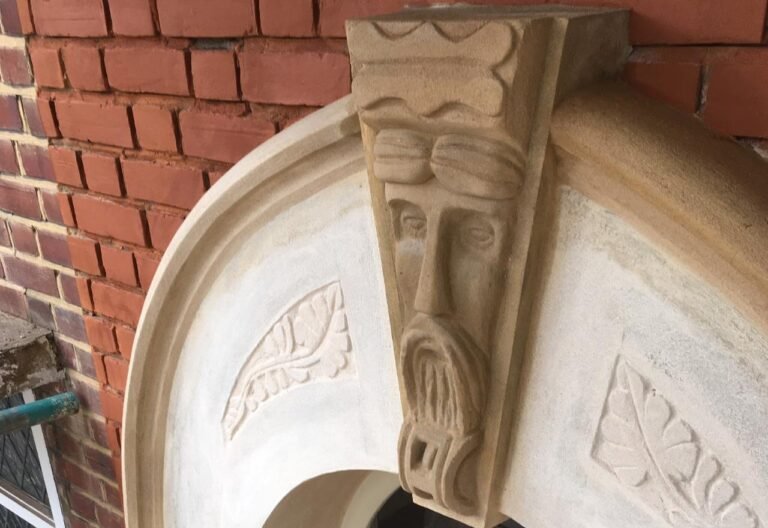 Detailed stone carving on a brick building, showcasing craftsmanship and restoration.