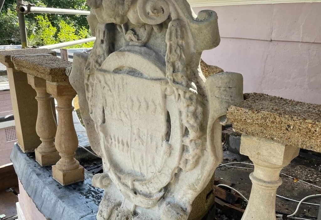 Close-up of a stone crest and balustrade, likely showing restoration work.