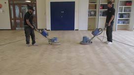 Two workers sanding a herringbone floor