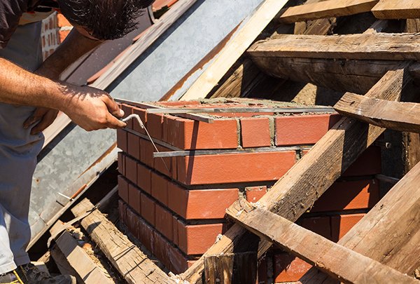 Bricklayer working on a chimney, showing construction process.