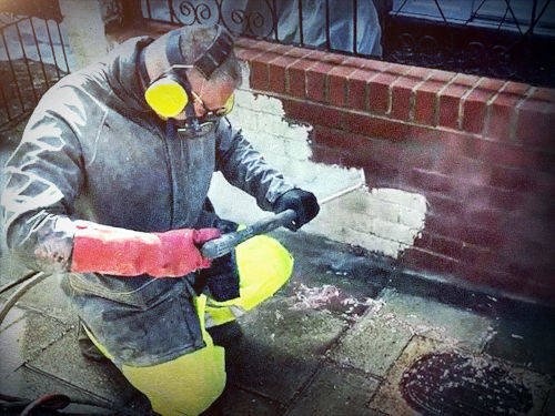 Close-up of brick cleaning with safety gear.