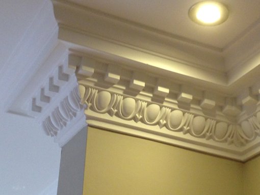 Detailed plasterwork on a ceiling corner, showcasing ornate design.