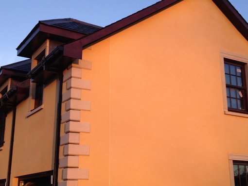 Exterior of a house with visible plastering work, possibly rendering or decorative elements.
