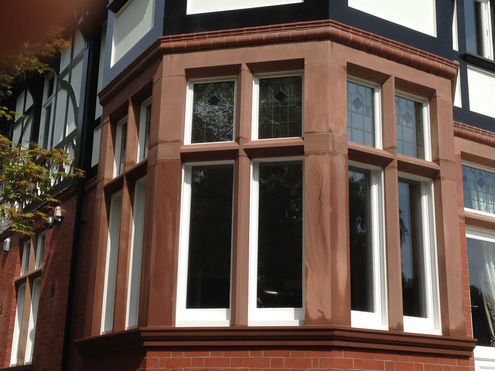 Bay window with stone detailing, showcasing restoration or construction work on a period home.