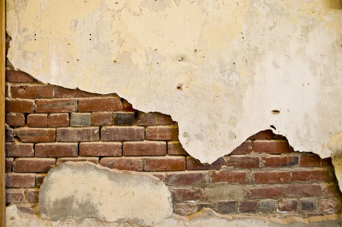 Damaged brick wall with plaster