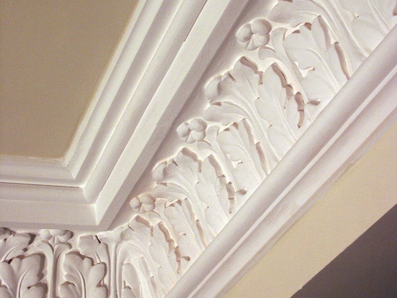 Close-up of plaster cornice with floral and leaf design.
