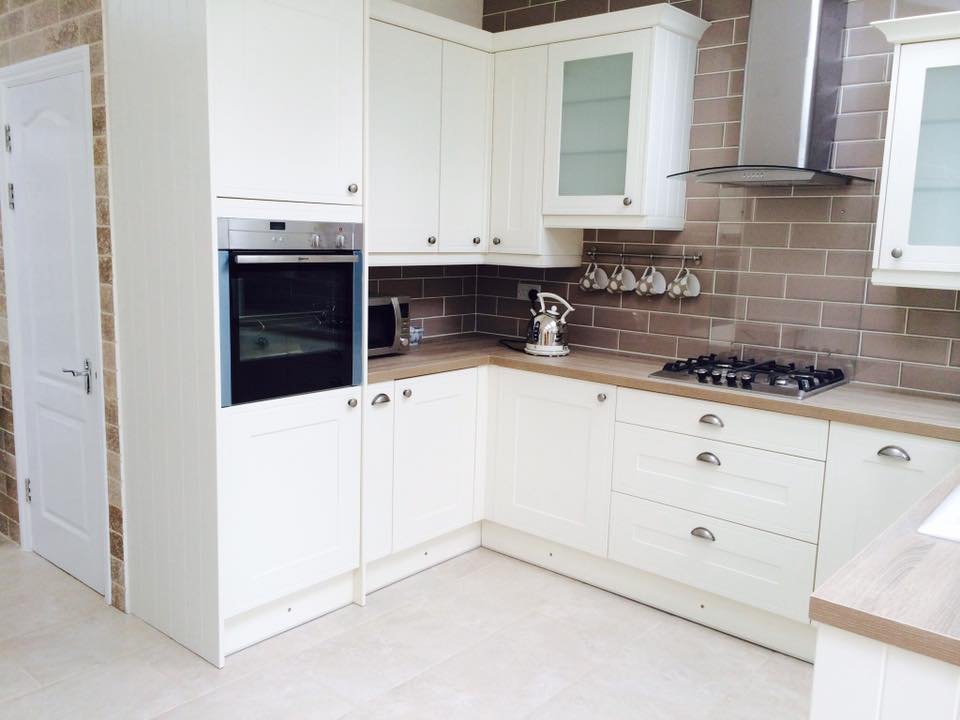 Modern kitchen renovation with white cabinets and tiled backsplash.