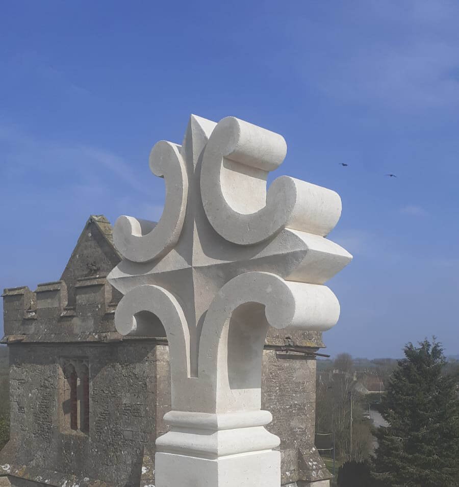 Restored or newly built stone cross atop a building, showcasing stonemasonry skills.