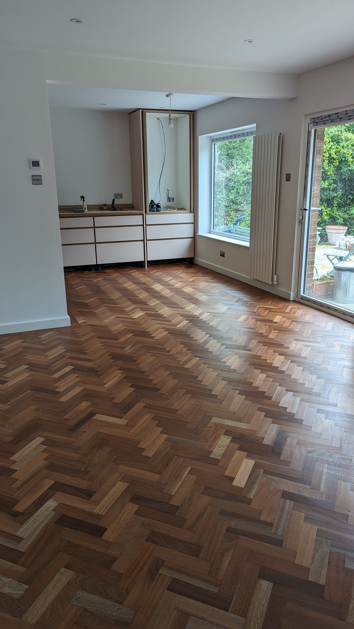 Herringbone wood floor in a room with a kitchen area.