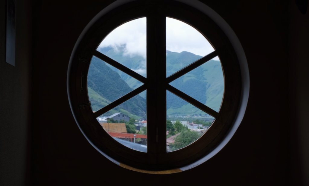 Round timber window with mountain view.
