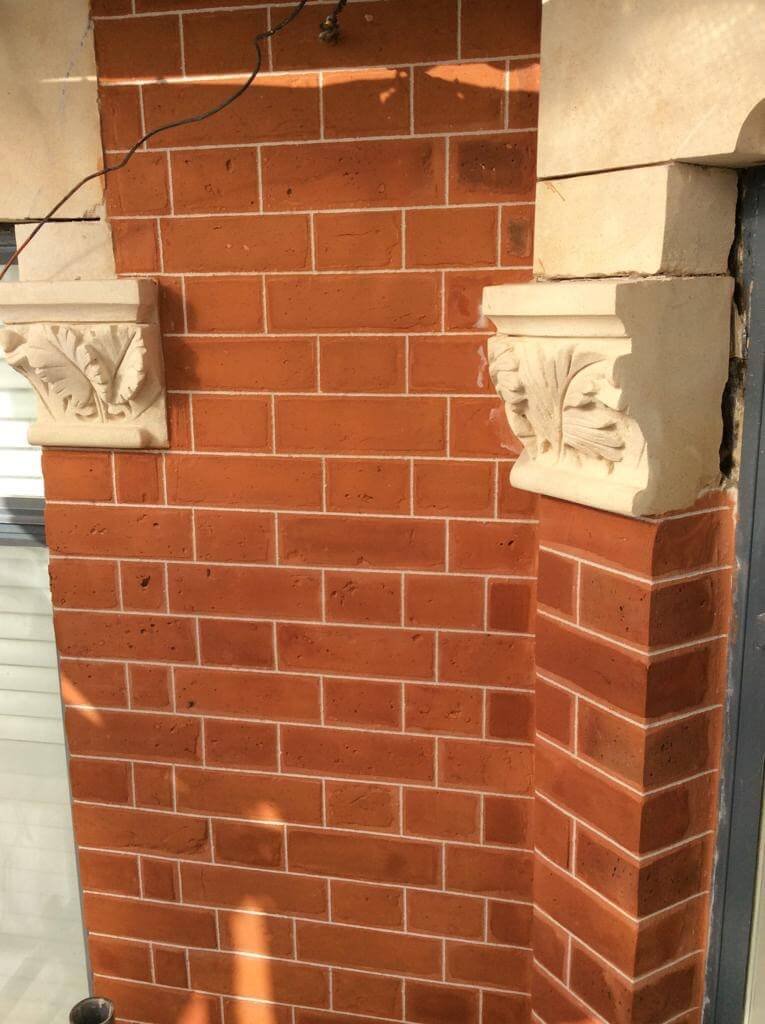 Brick wall with restored pointing and stonework details.