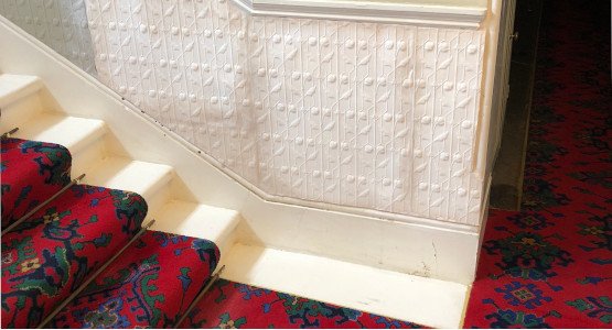 Staircase with ornate plasterwork on the wall.