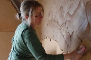 Plasterer removing old plaster.