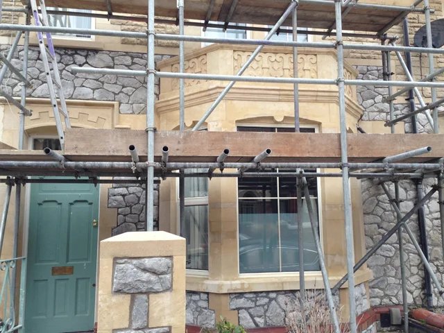 Stone house under restoration with scaffolding.