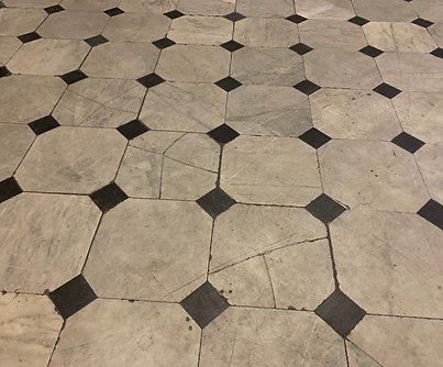 Marble tile floor before restoration, showing cracks and wear.
