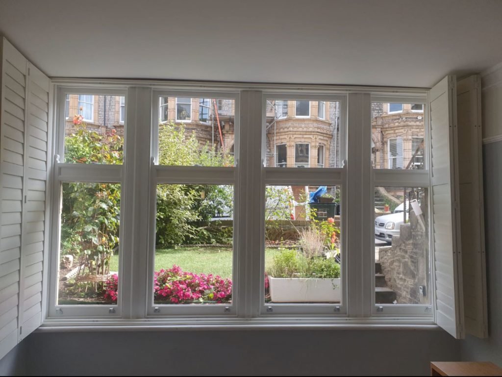 Interior view of restored timber windows with shutters, showcasing the view.