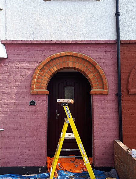 Shows brickwork and pointing around a doorway, with a ladder suggesting ongoing work.