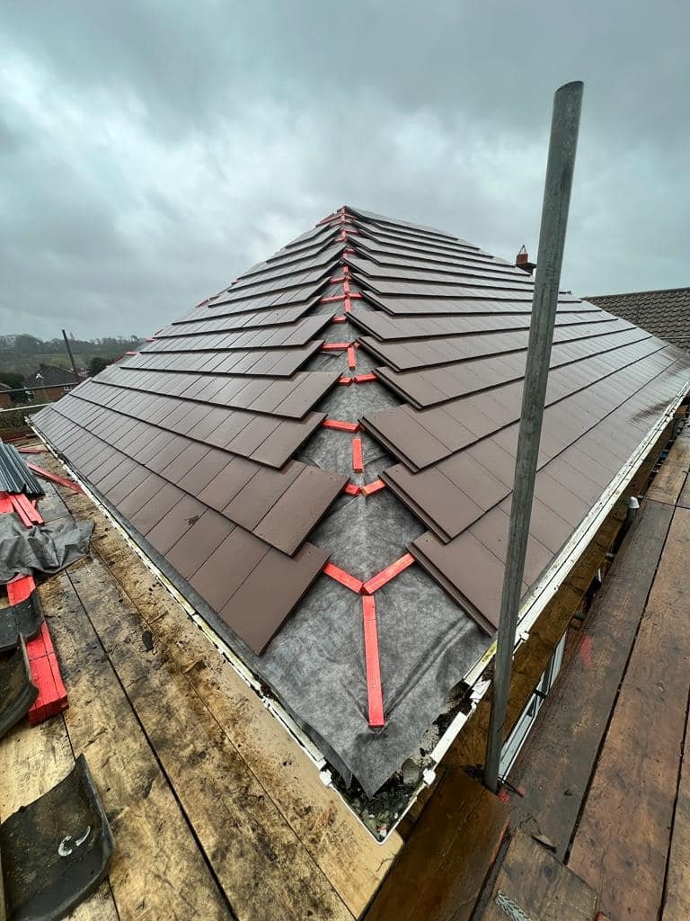 Roof under construction with battens and tiles being installed.
